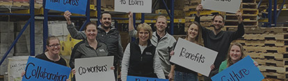 Employees holding signs in warehouse